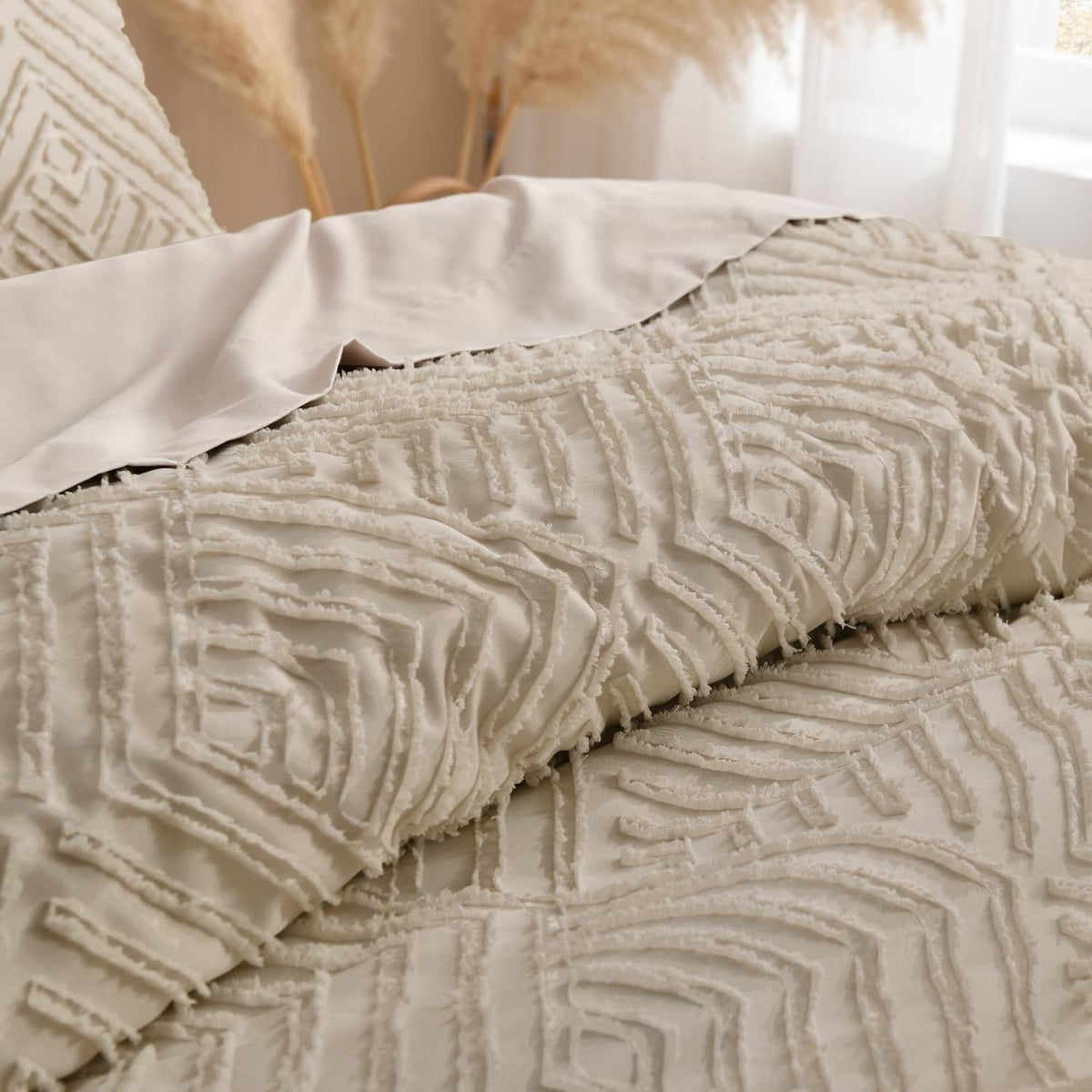 Close-up of light beige quilted comforter with raised geometric stitching and fringe edges