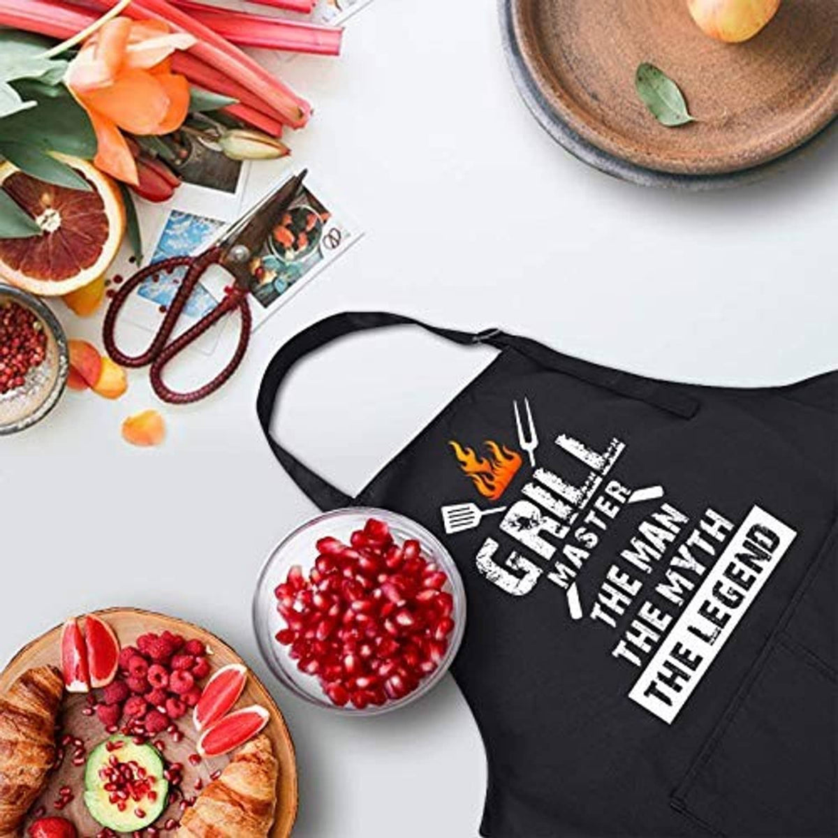 Black BBQ apron with flame Grill Master logo and slogan print, lying flat