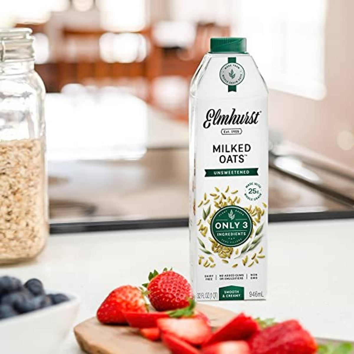 Unsweetened oat milk carton on kitchen counter with strawberries nearby.