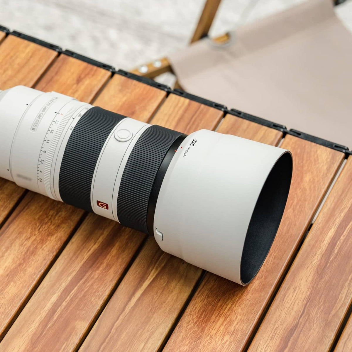 White lens hood fitted on a black-and-white Sony FE 70-200mm telephoto lens