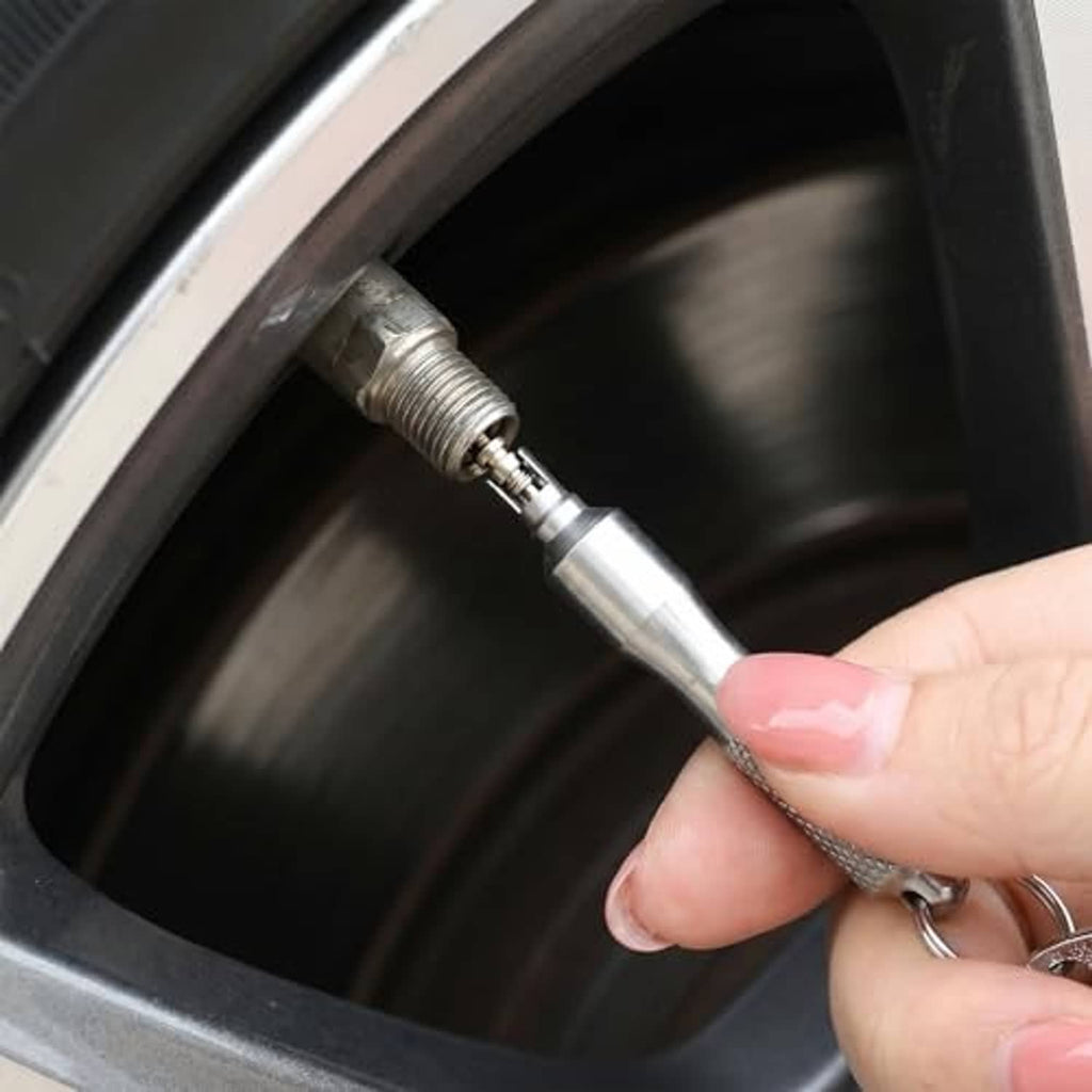 Valve stem remover tool with textured grip, inserting tip into tire valve stem