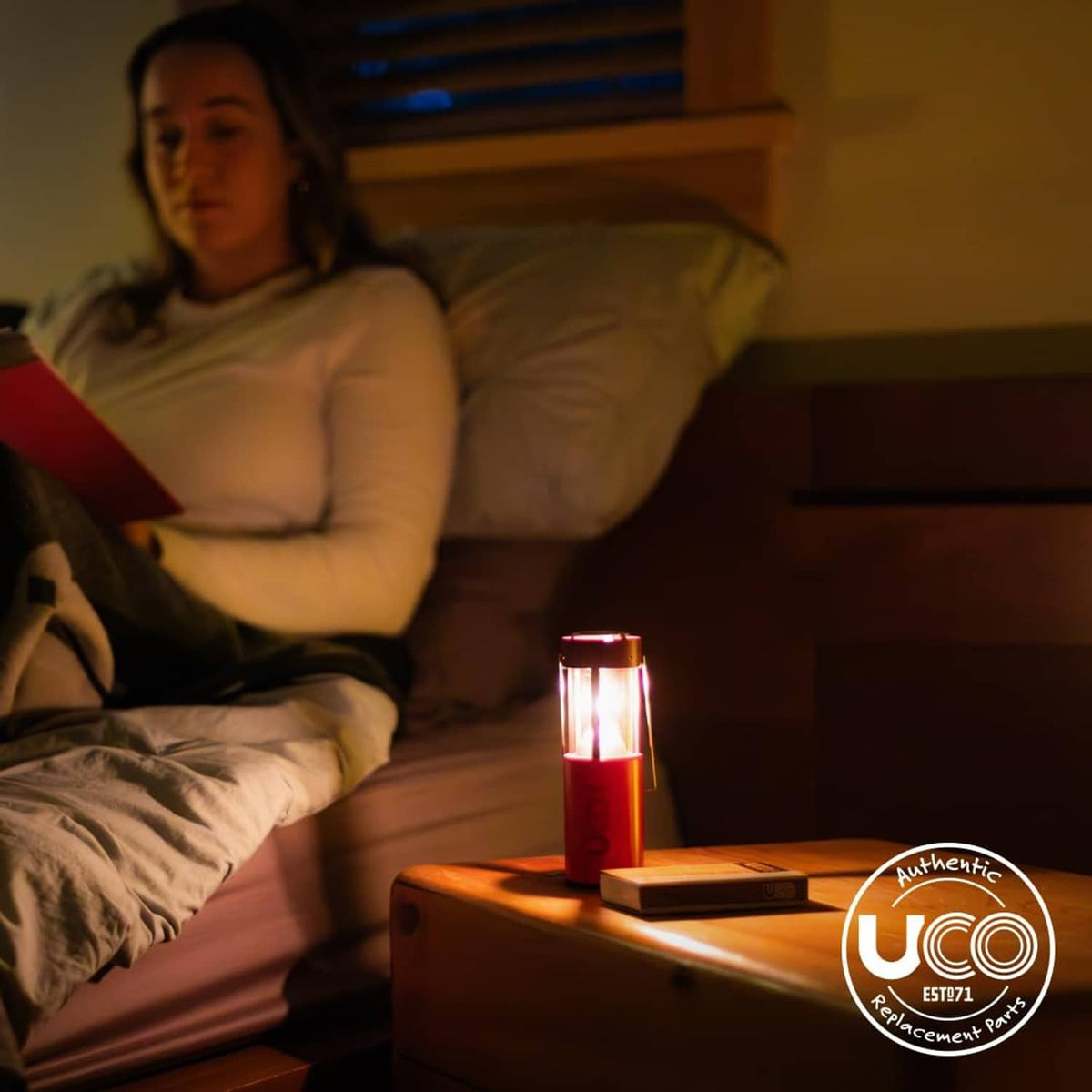 Lit natural beeswax survival candle on nightstand with warm glow