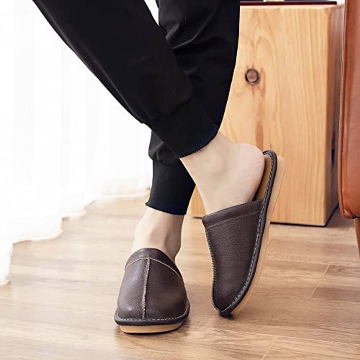 Dark brown leather slip-on slippers worn while walking, open collar and stitched trim