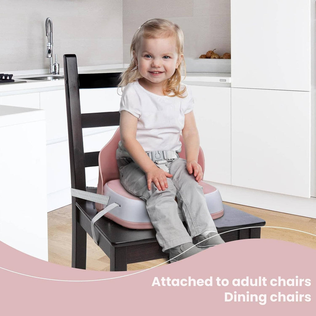 Baby seated in a pink booster seat attached to a dining chair