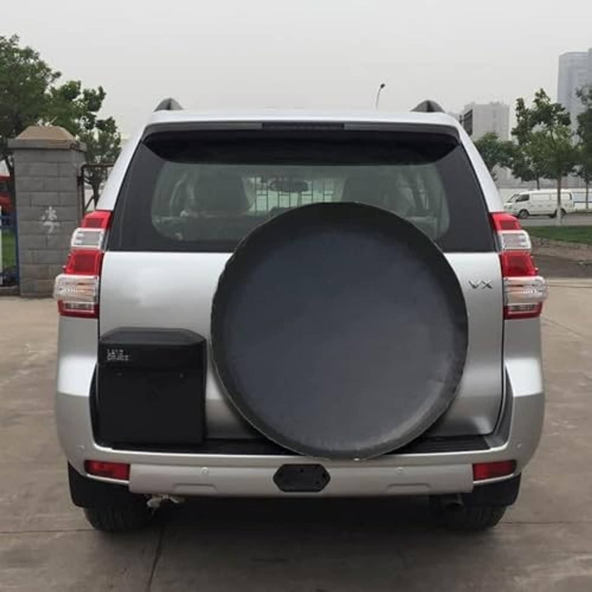 Universal spare tire cover on SUV rear hatch area, round dark gray/black cover