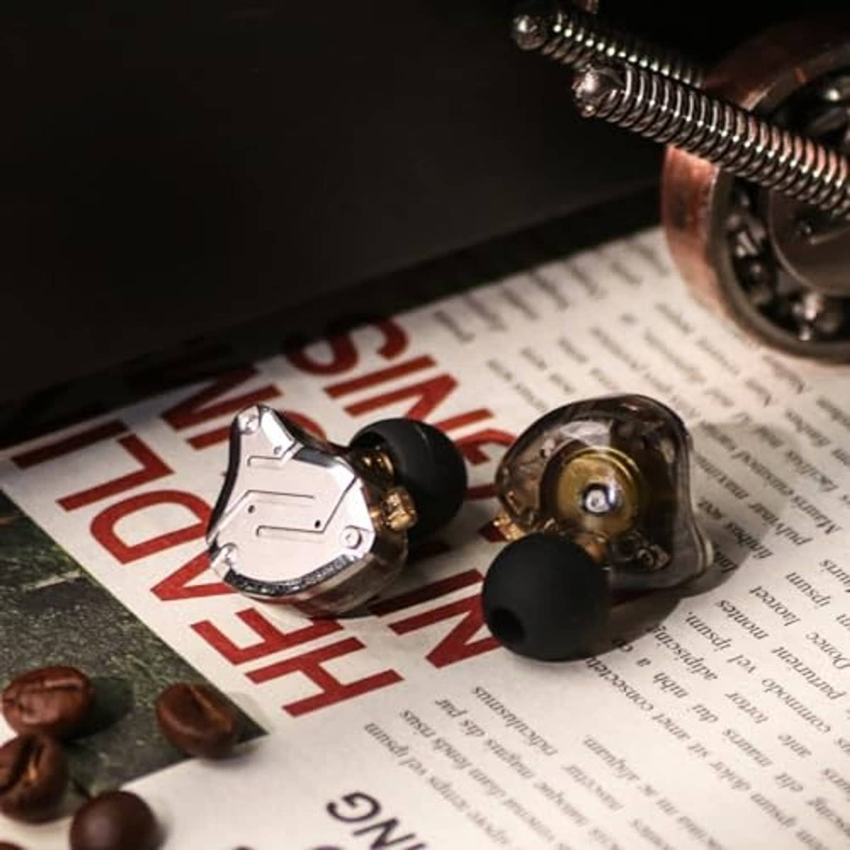 In-ear monitor earbuds with clear cable and silver metal housings on printed materials