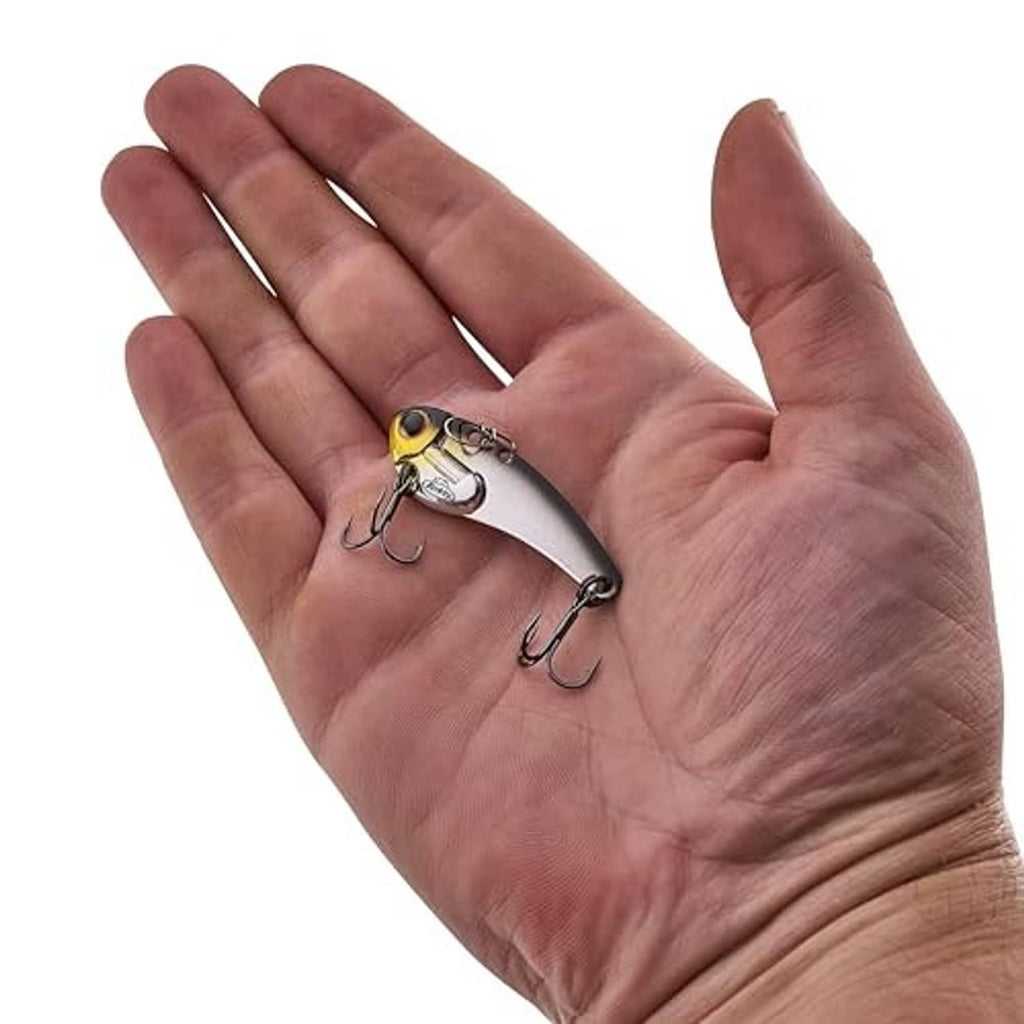 Blade bait fishing lure held in hand, black-silver body with treble hooks
