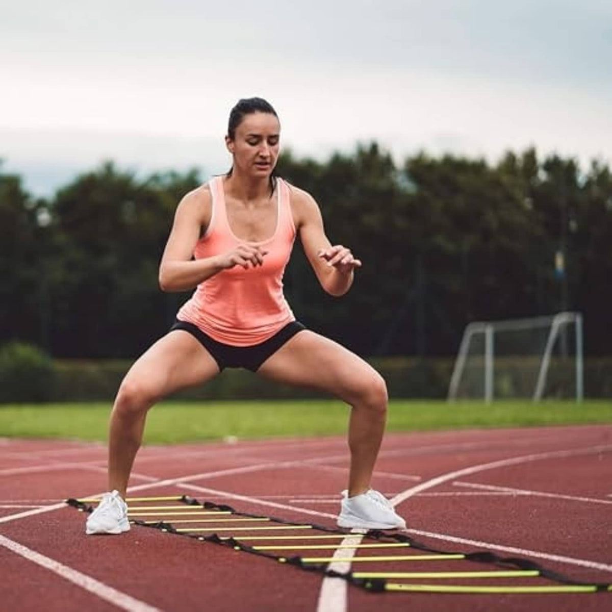 Agility ladder with bright yellow rungs and black side rails on a running track