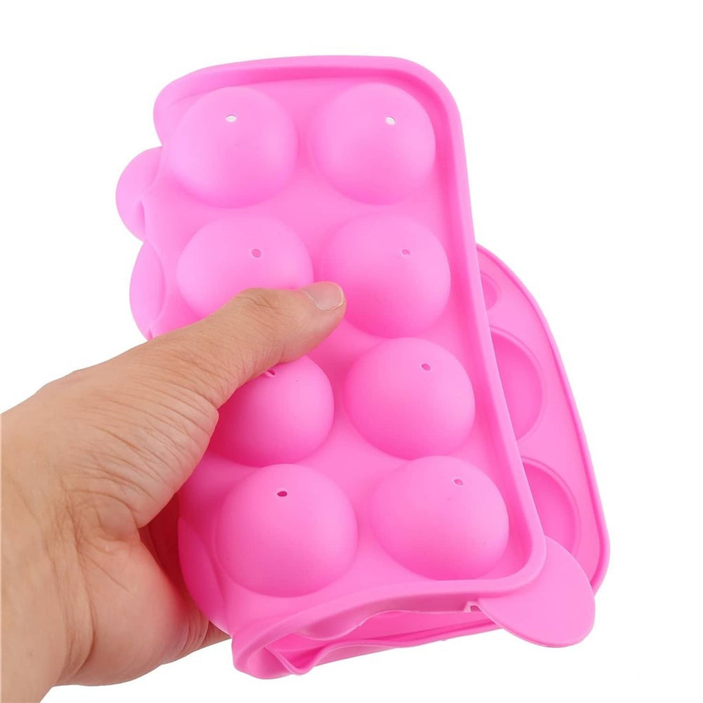 Pink silicone cake pop mold tray with a hand pressing into the cavities