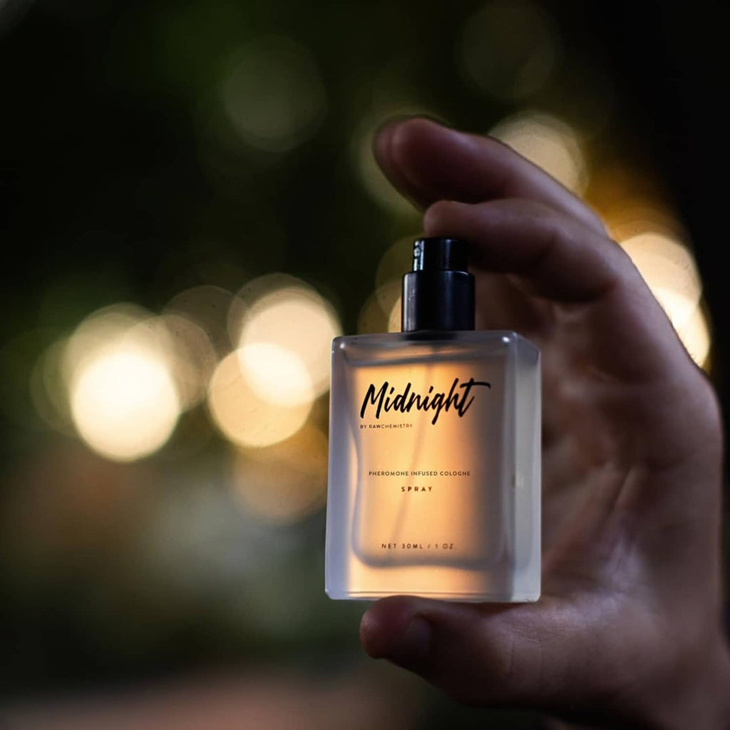 Men's cologne spray bottle held in a hand, black cap and Midnight label