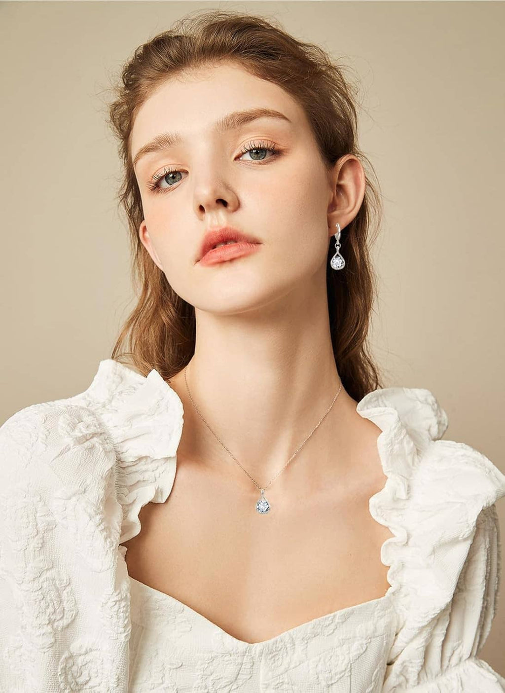 Woman wearing a silver crystal teardrop necklace and matching dangle earrings