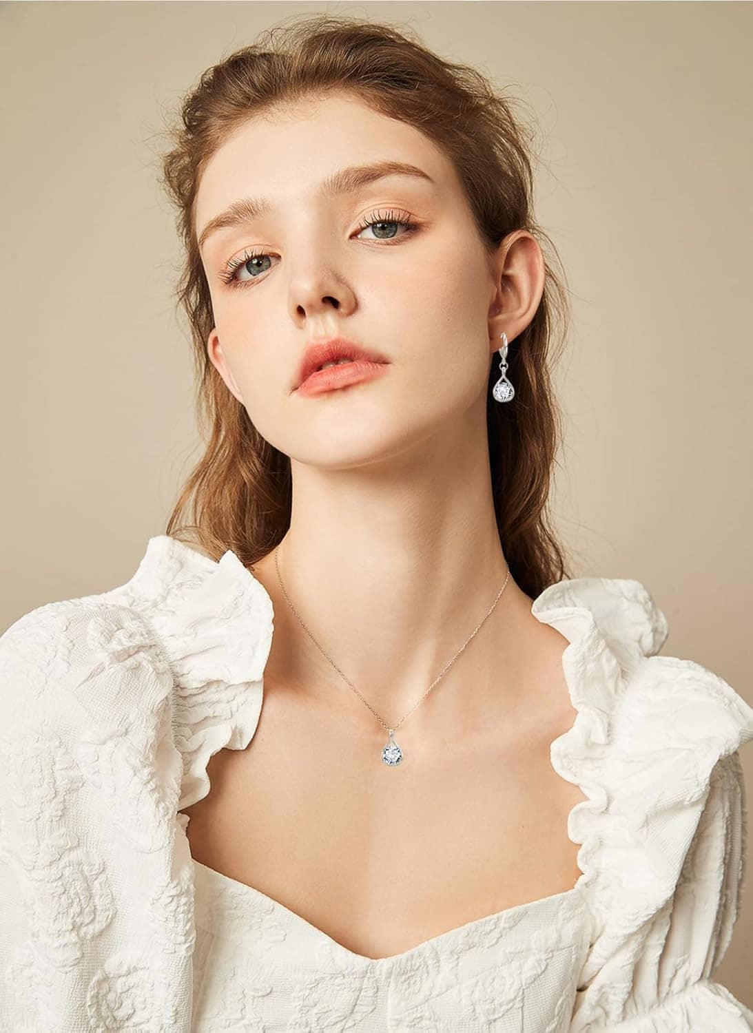 Woman wearing a silver crystal teardrop necklace and matching dangle earrings
