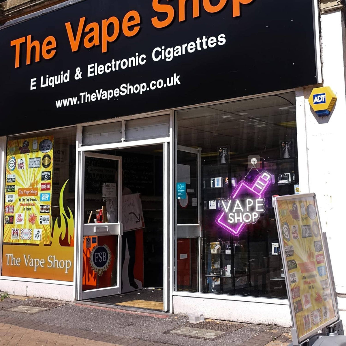 VAPE SHOP neon sign displayed in a storefront window with pink arrow outline and white letters