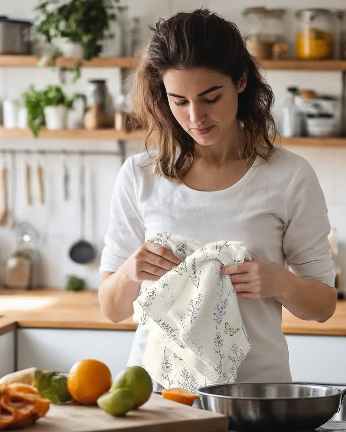 White kitchen towel in hands, featuring botanical sprigs and butterfly print