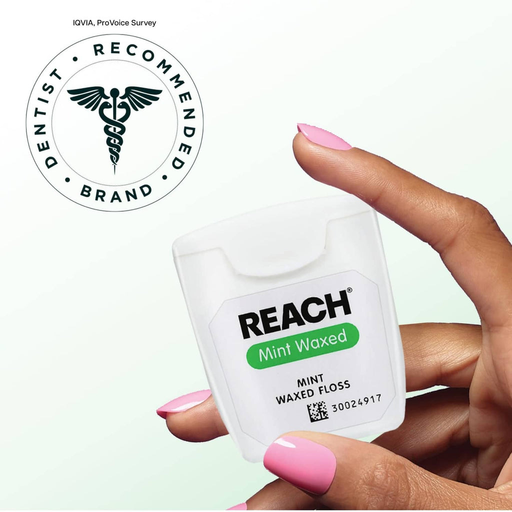 Reach mint waxed dental floss shown in hand, white and green label
