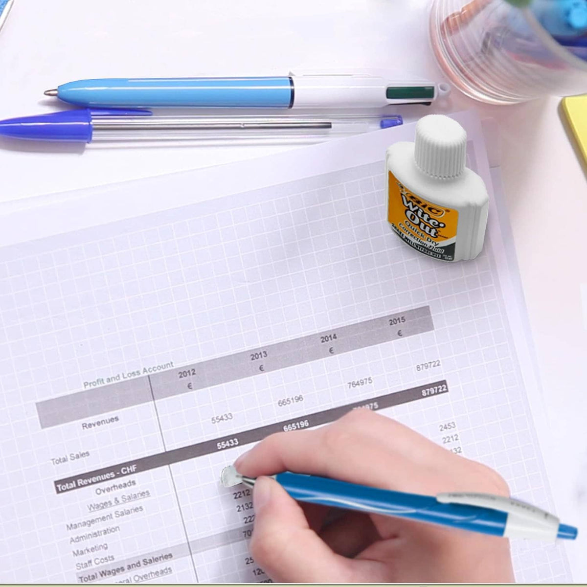 Correction fluid bottle and blue pen on graph paper for writing corrections
