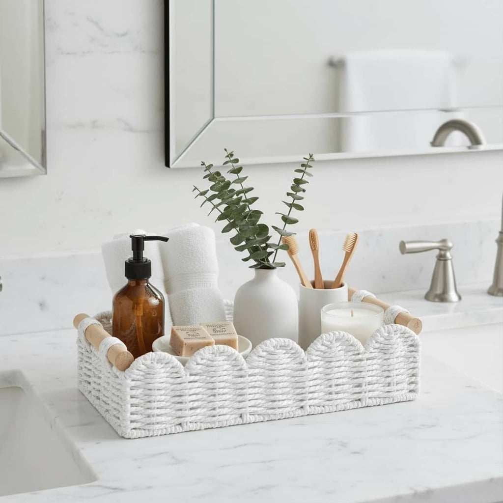 White woven storage basket with rope handles holding toiletries and paper towels on bathroom counter