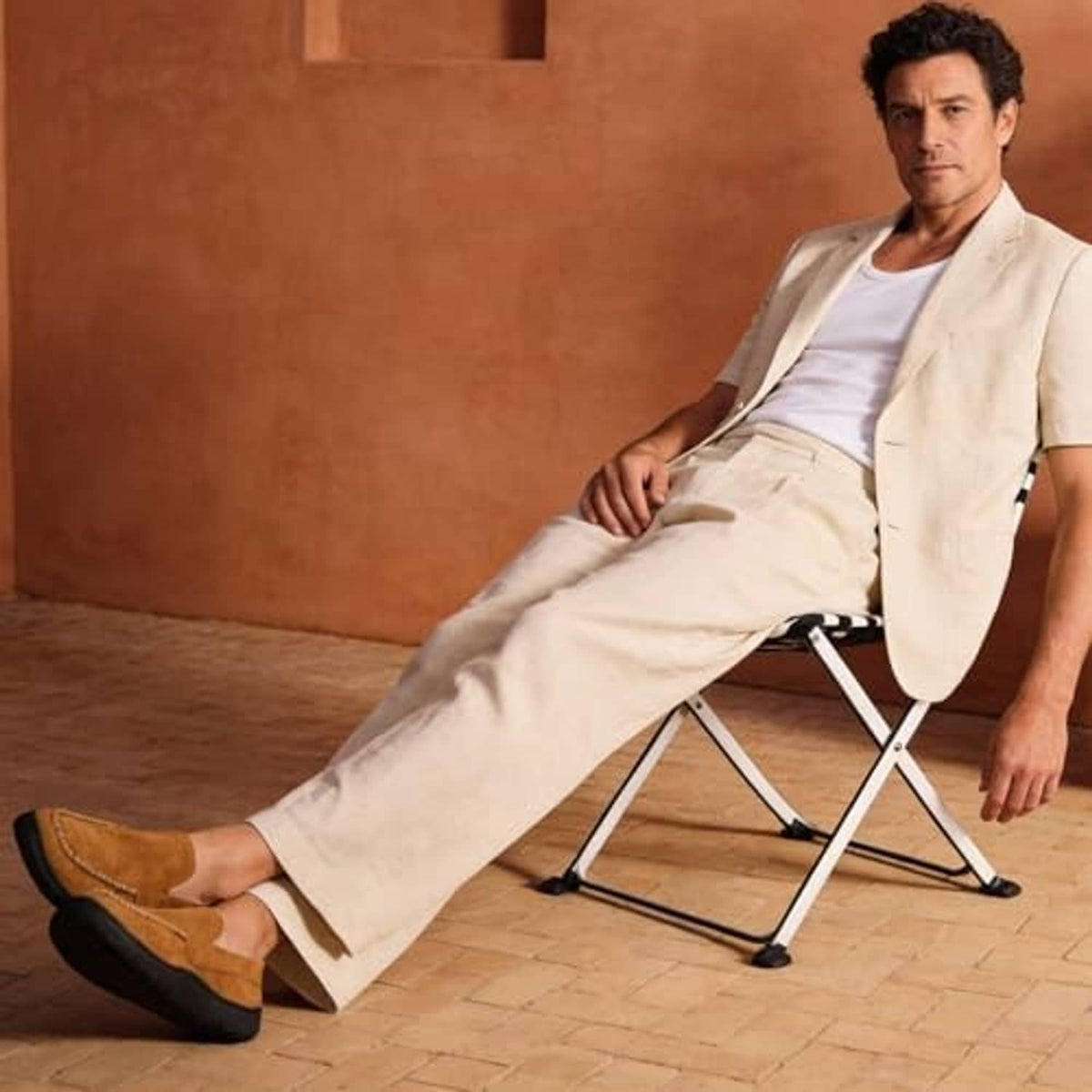 Brown slip-on moccasin slippers with plush lining and black sole worn on feet