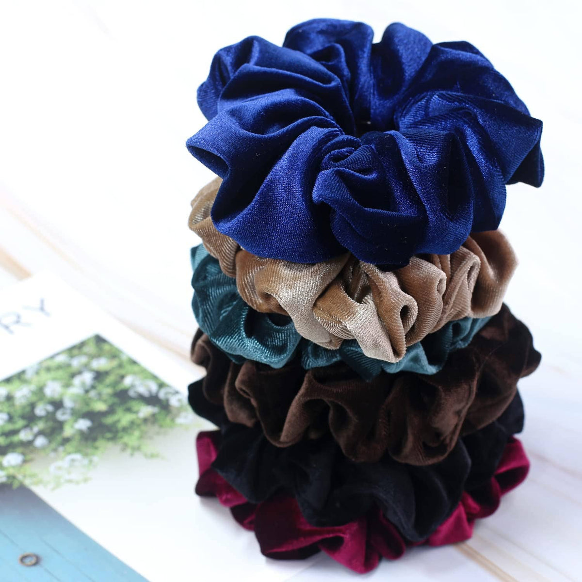 Velvet scrunchies in blue, tan, brown, and teal worn on hair