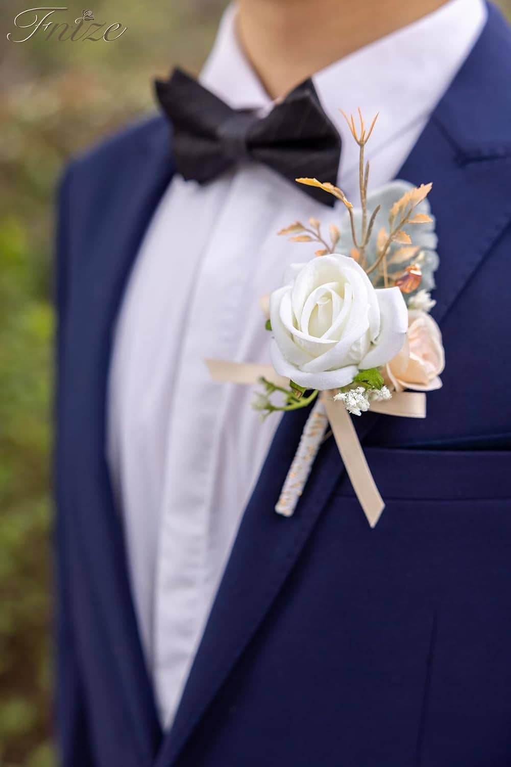 Boutonniere on a navy suit jacket lapel: white rose with greenery and champagne ribbon