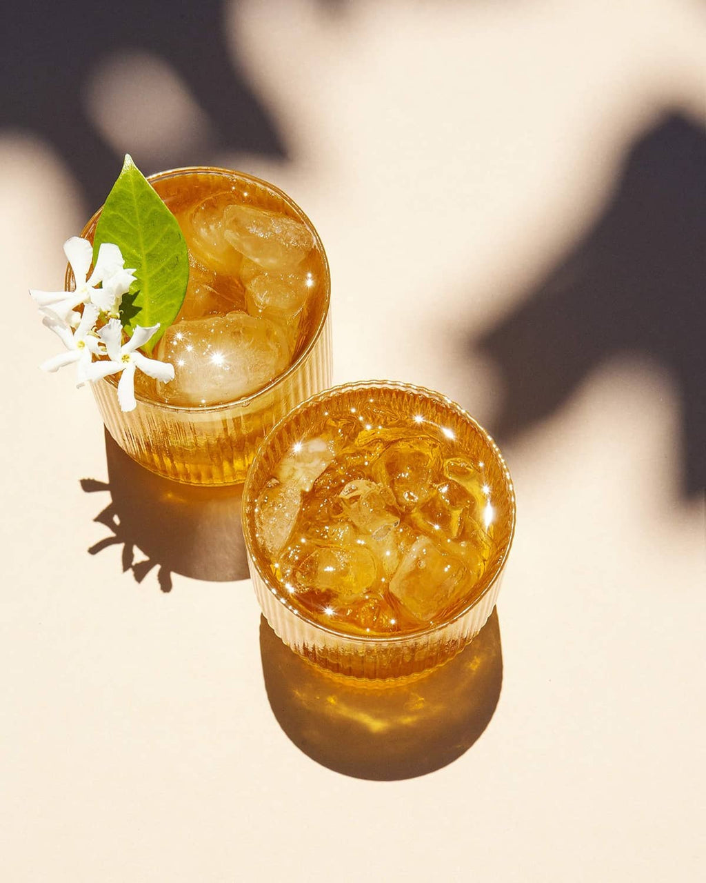 Two glasses of iced jasmine green tea with leaf and flower garnish