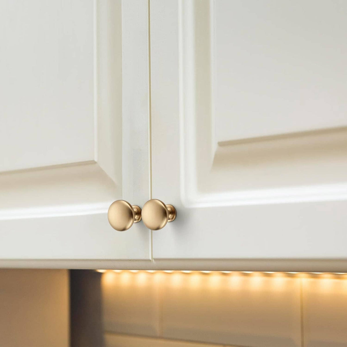 Champagne bronze round cabinet knob mounted on white cabinet door