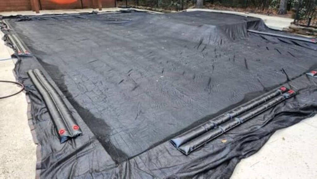 Black shade cloth laid out flat with reinforced seams and grommet edges