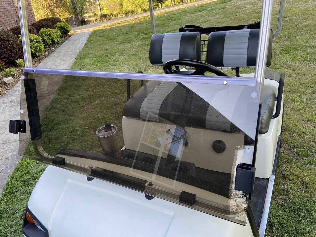 Tinted folding golf cart windshield installed over the front seats, clear smoky glass