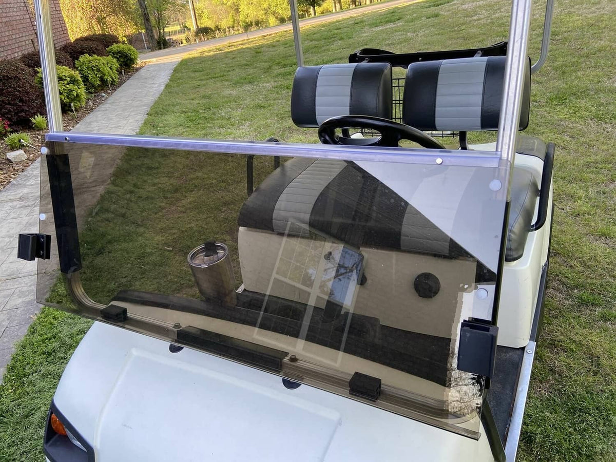 Tinted folding golf cart windshield installed over the front seats, clear smoky glass