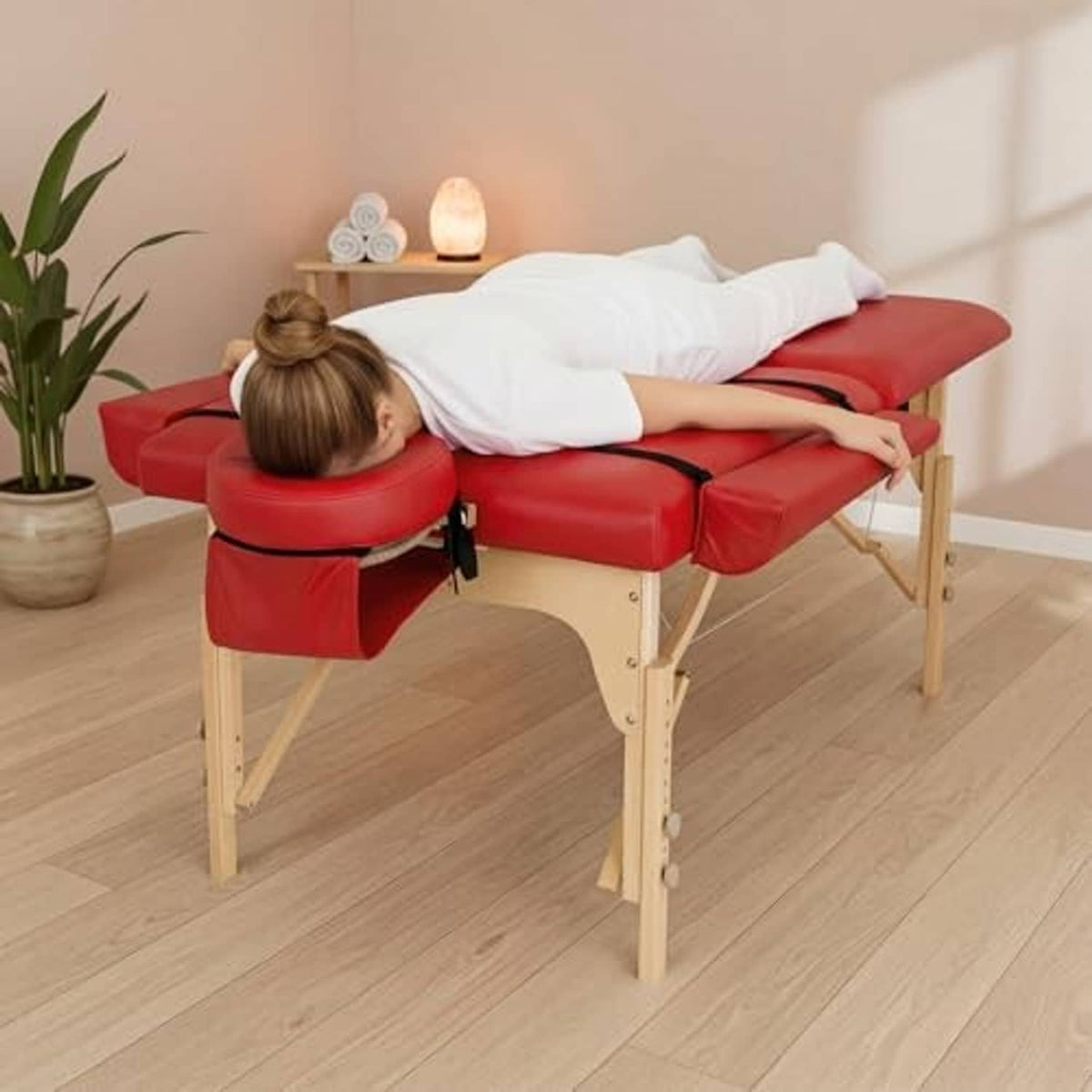 Red padded massage table arm rest bolsters on wooden frame with head cutout