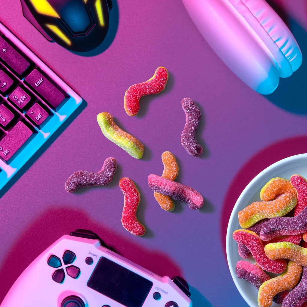 Mixed sour gummi crawlers candy pieces scattered near a bowl