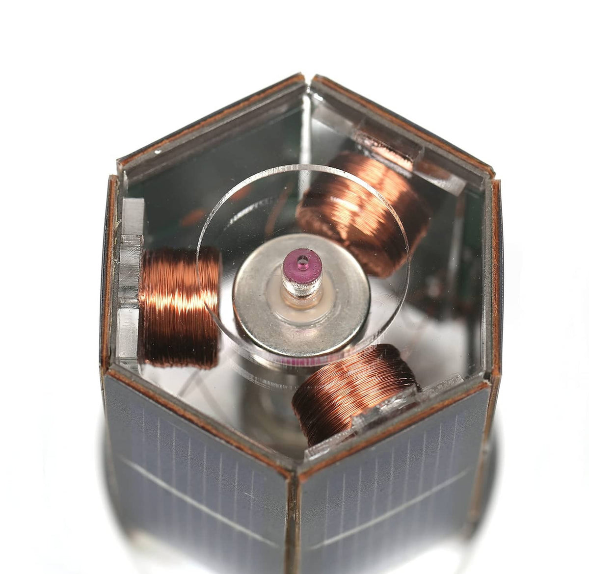 Solar motor toy close-up of copper coils and circular motor rotor inside blue panel cube