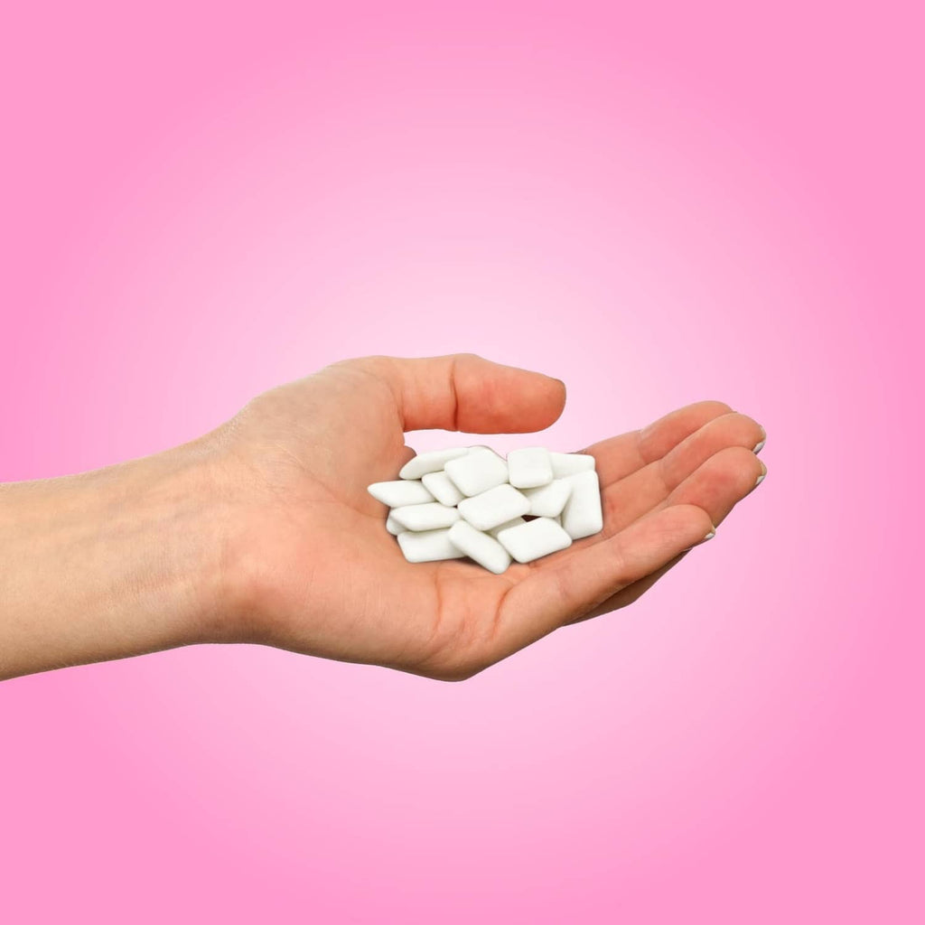 Bubblegum gum pieces held in an open palm, white xylitol gum