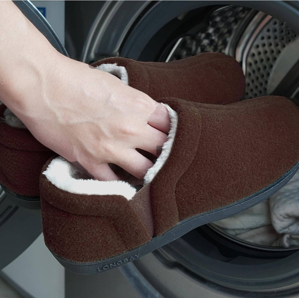 Brown slip-on slippers with beige sherpa trim, hand adjusting the cuff