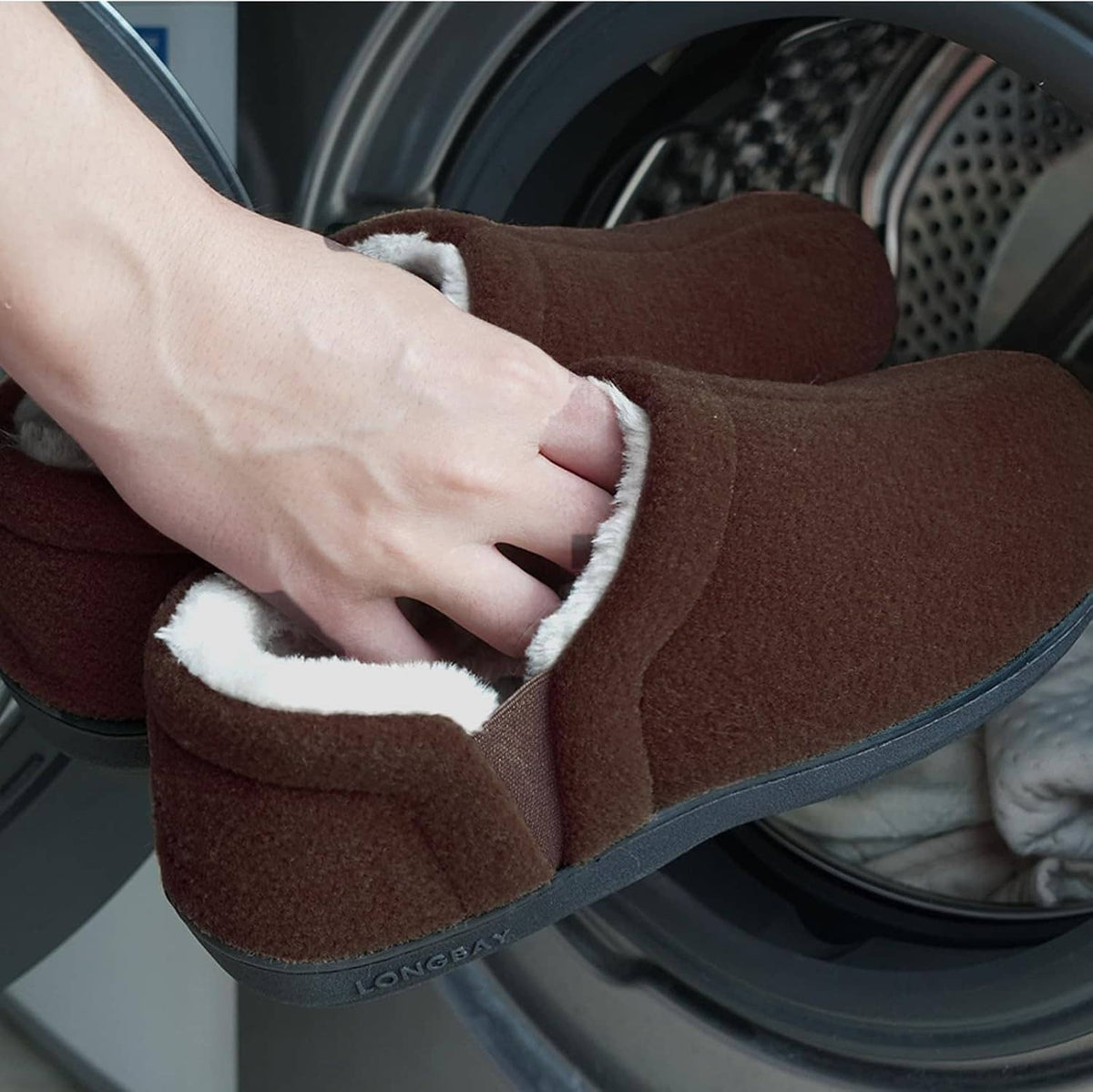 Brown slip-on slippers with beige sherpa trim, hand adjusting the cuff