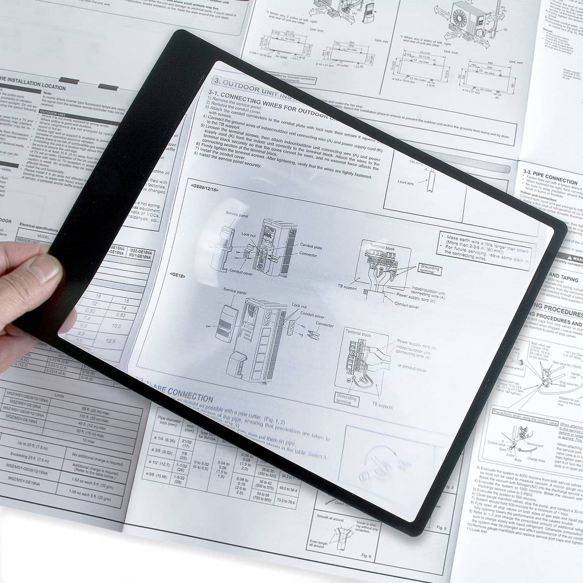 Carson flexible magnifier over engineering diagrams on paper, black frame