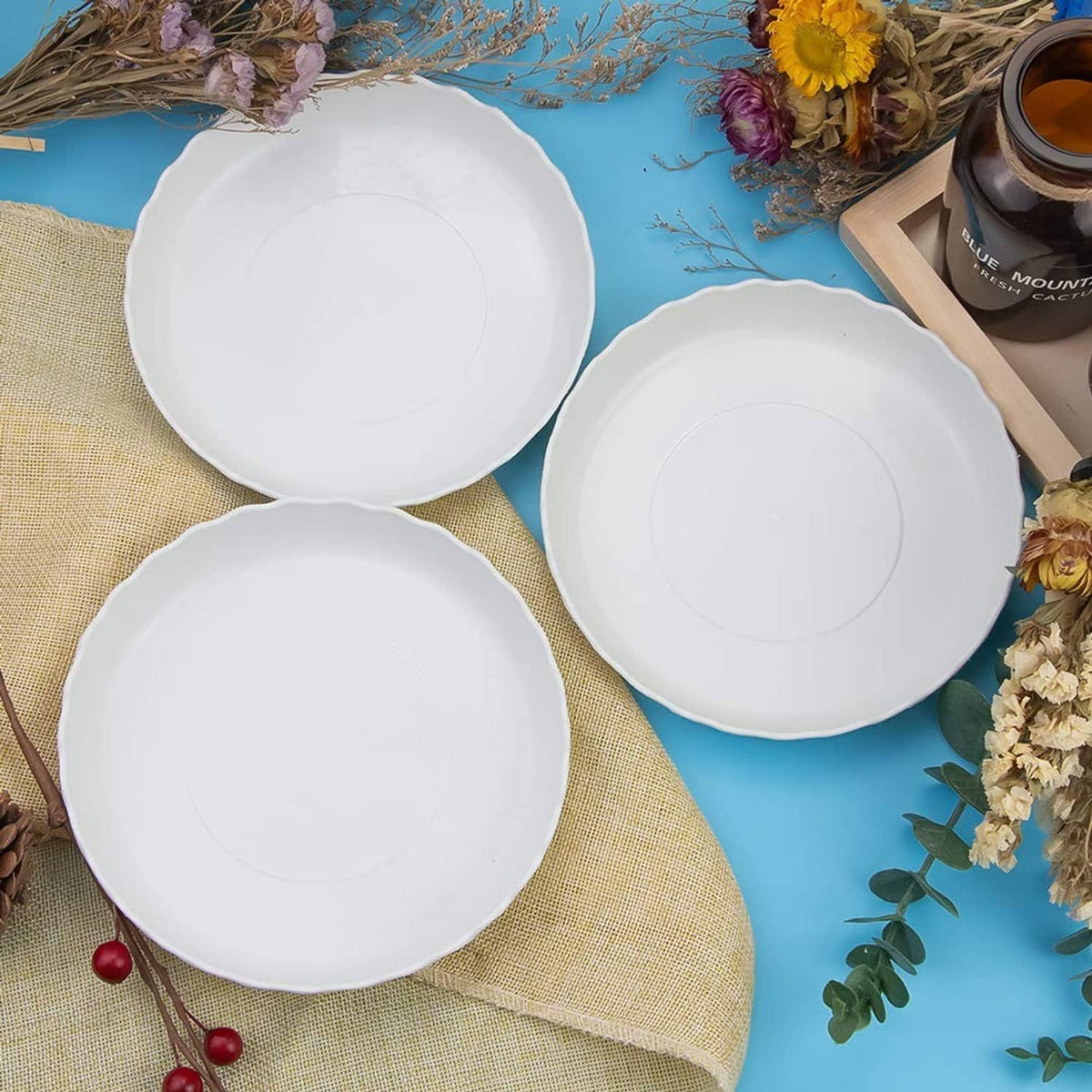 Three white round plastic plates with wavy scalloped rims