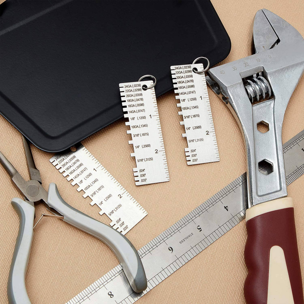Metal thickness gauge set with multiple etched cards and measuring scale alongside tool