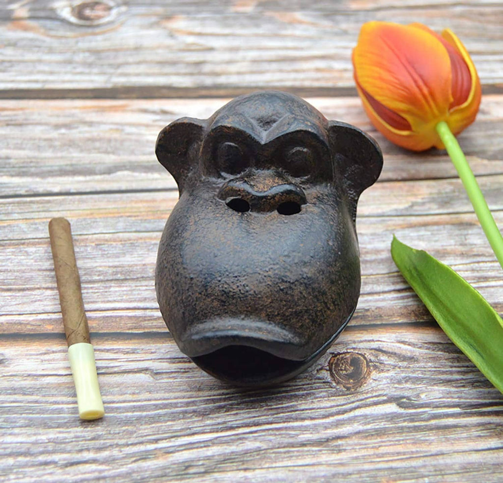 Monkey face cast ashtray with cigarette sticks on top, dark brown finish