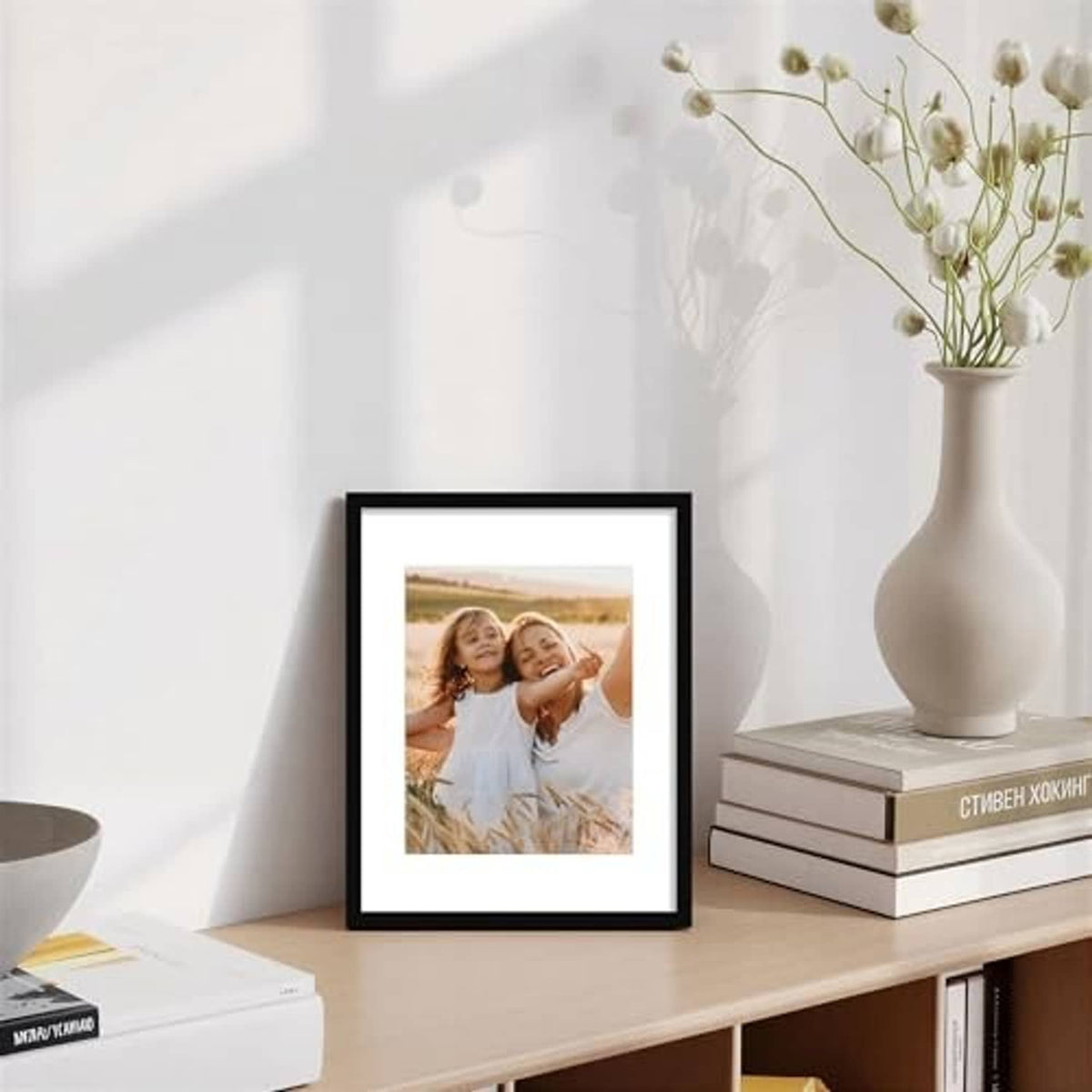 Small black picture frame with real glass, standing on a shelf with a vase nearby
