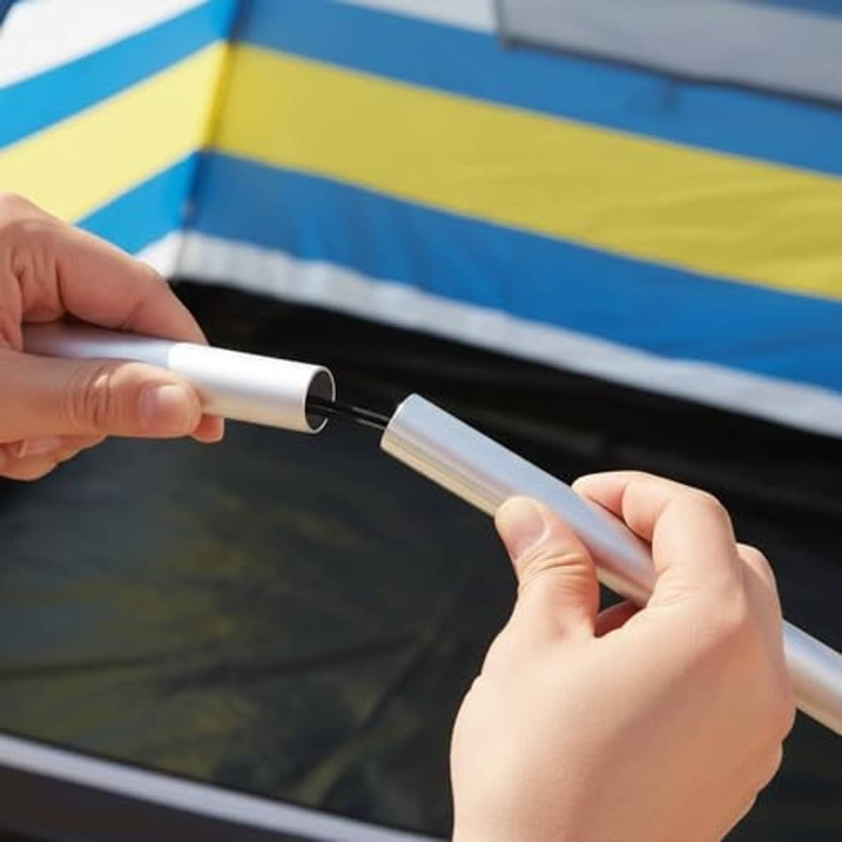 Aluminum tent pole being inserted into fabric sleeve with black connector ring