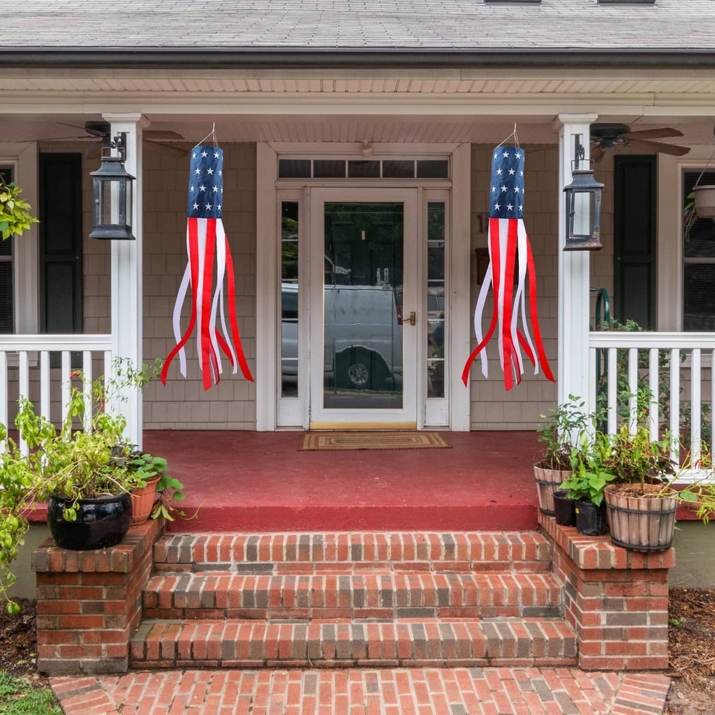 Two US flag windsocks hanging on house steps near the front entry