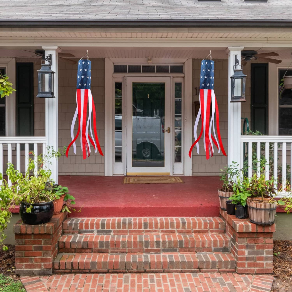 Two US flag windsocks hanging on house steps near the front entry