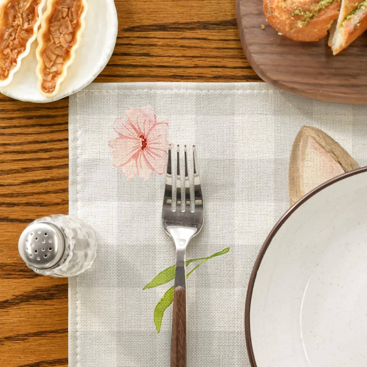 Beige plaid rectangular placemat with bunny-ear illustration and floral accents.