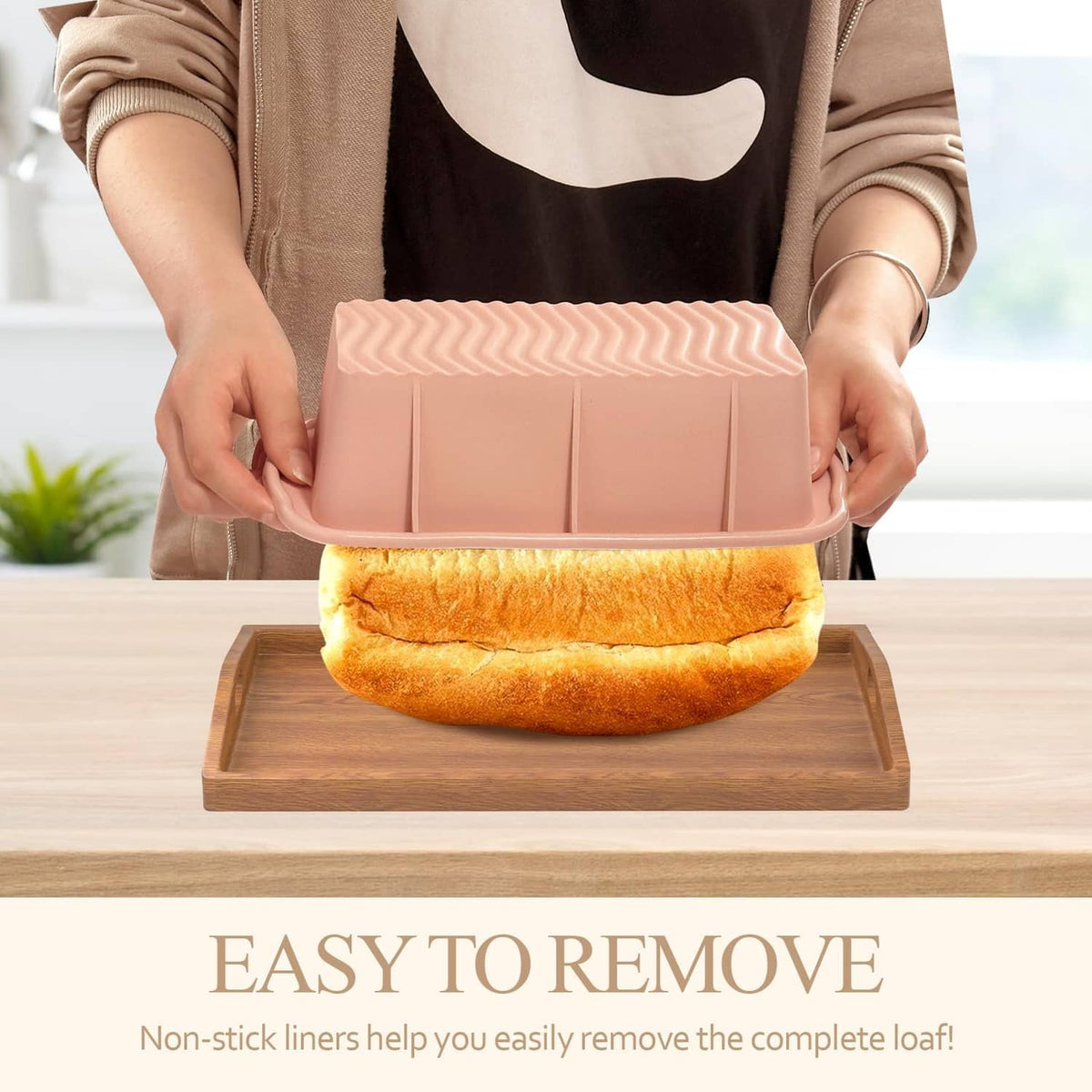 Pink silicone rectangular loaf pan being held with baked bread