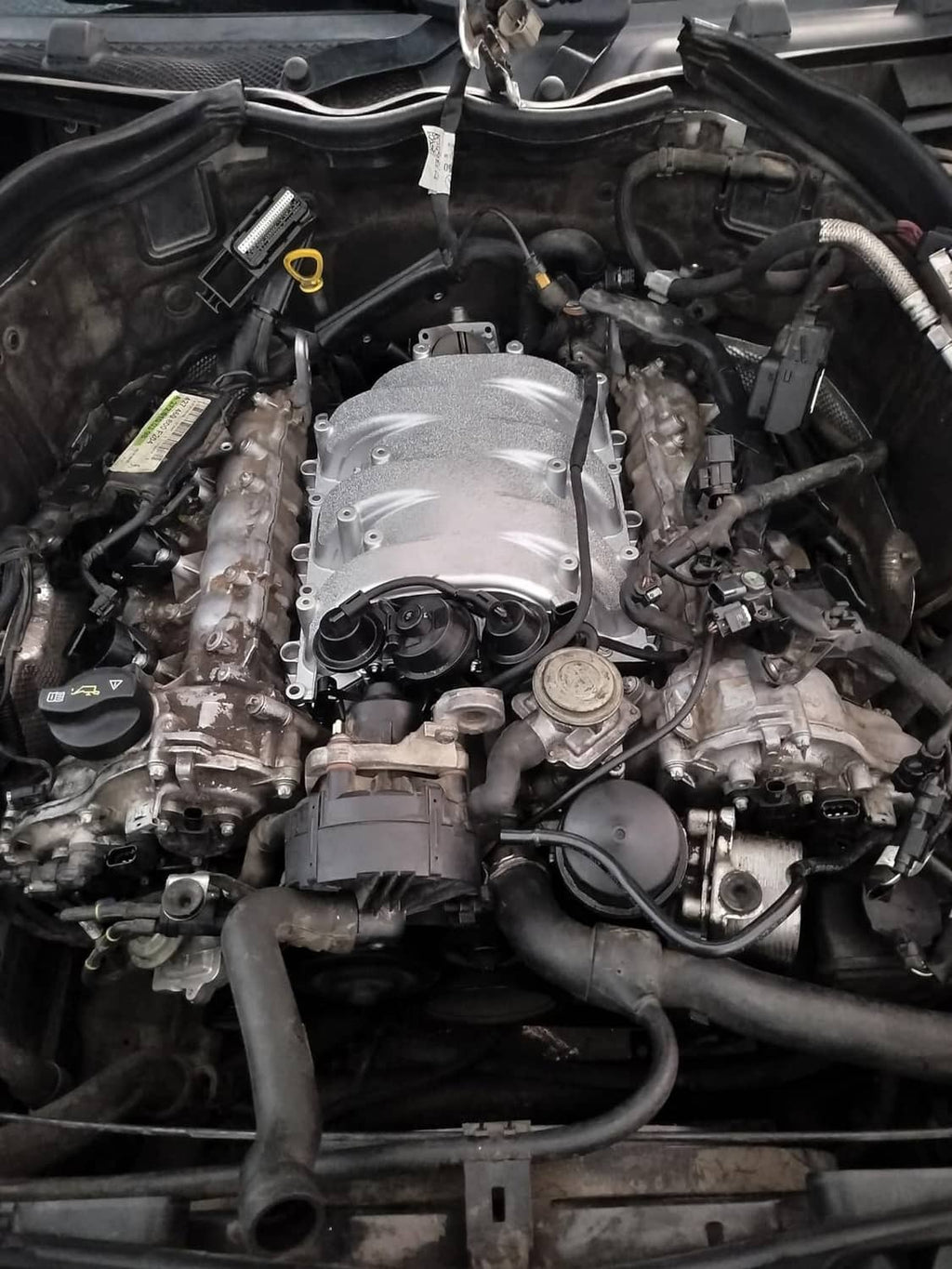 Installed silver intake manifold assembly in engine bay with connected hoses