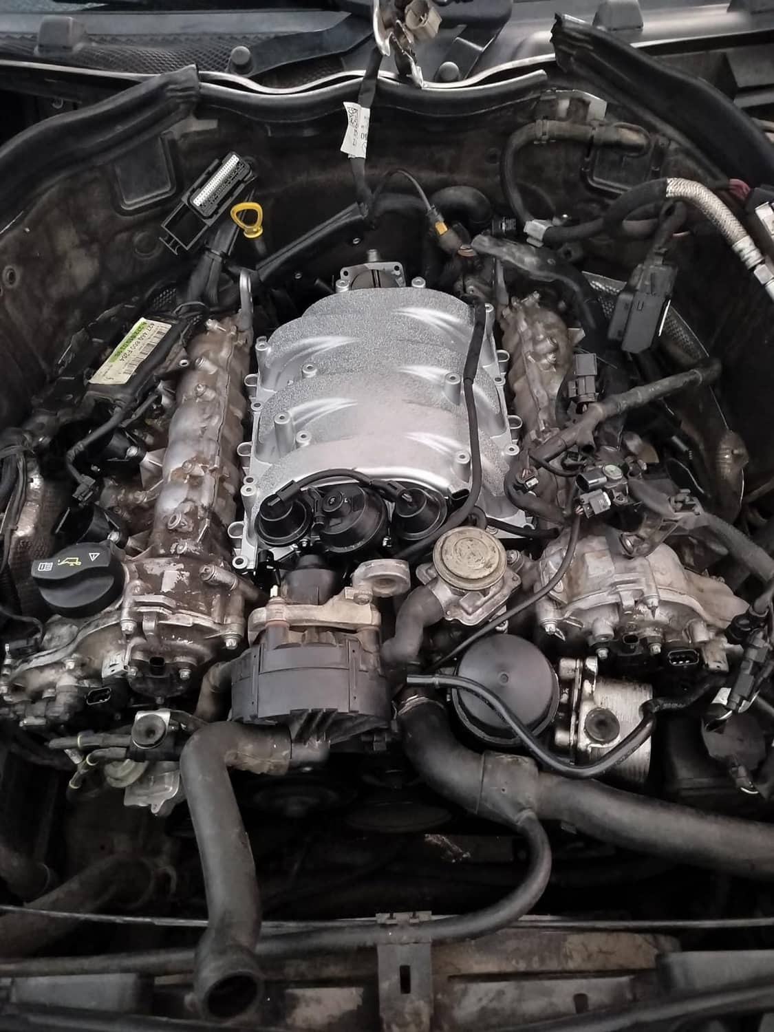 Installed silver intake manifold assembly in engine bay with connected hoses