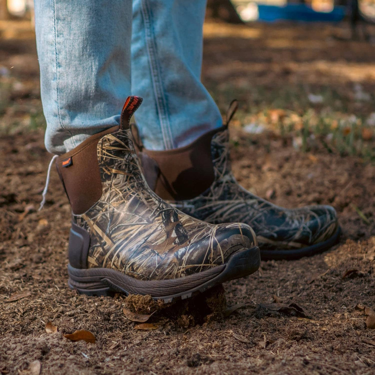 Camouflage waterproof rubber boots worn with jeans, showing lace-up shaft and tread