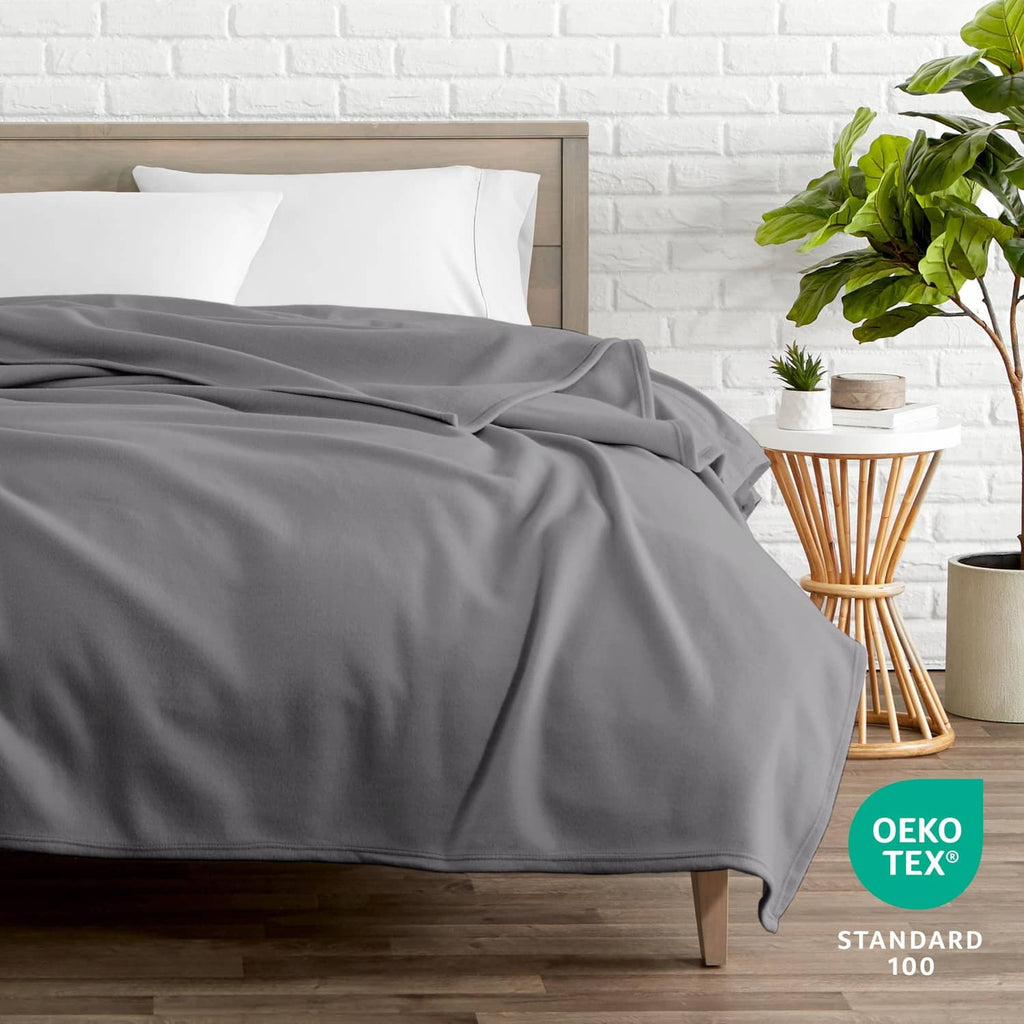 Gray full/queen blanket neatly spread across a bed, smooth woven texture