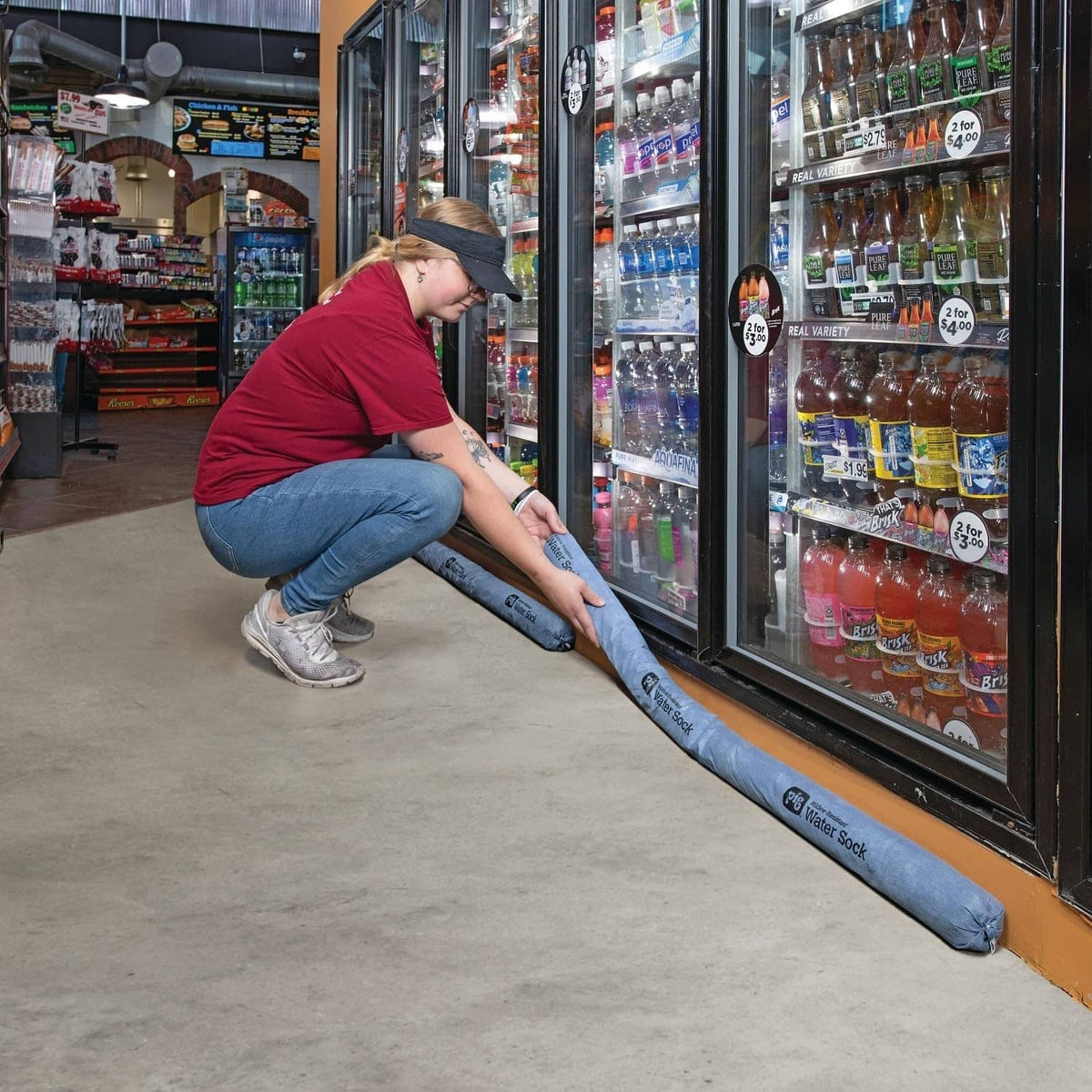 Blue absorbent sock barrier being placed along a refrigerator door opening